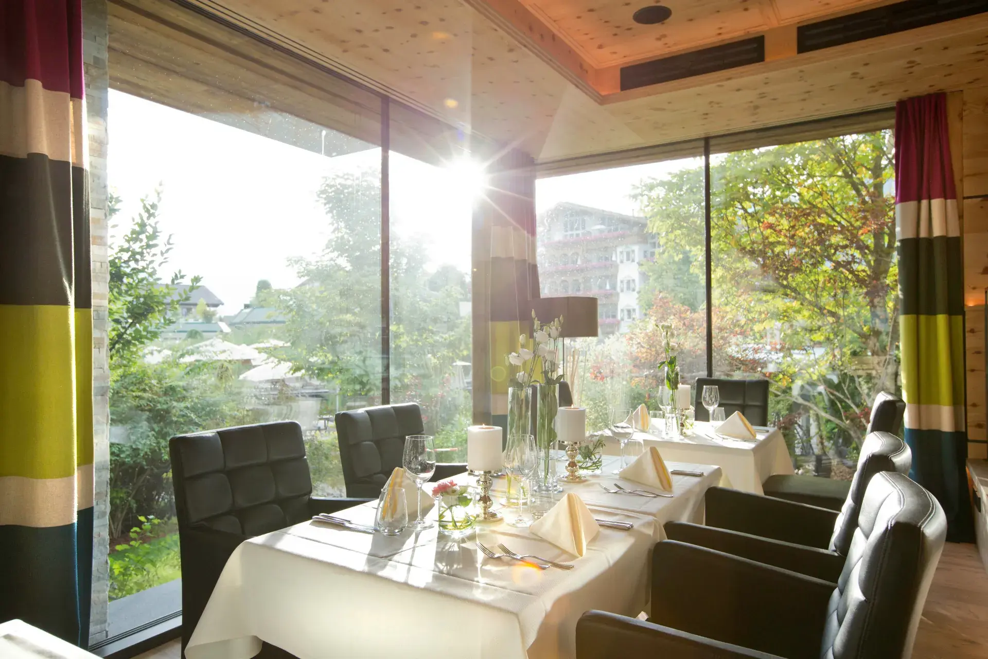 Laid tables in the Greenvieh Swiss-pine nook with garden views through large windows, Mieming