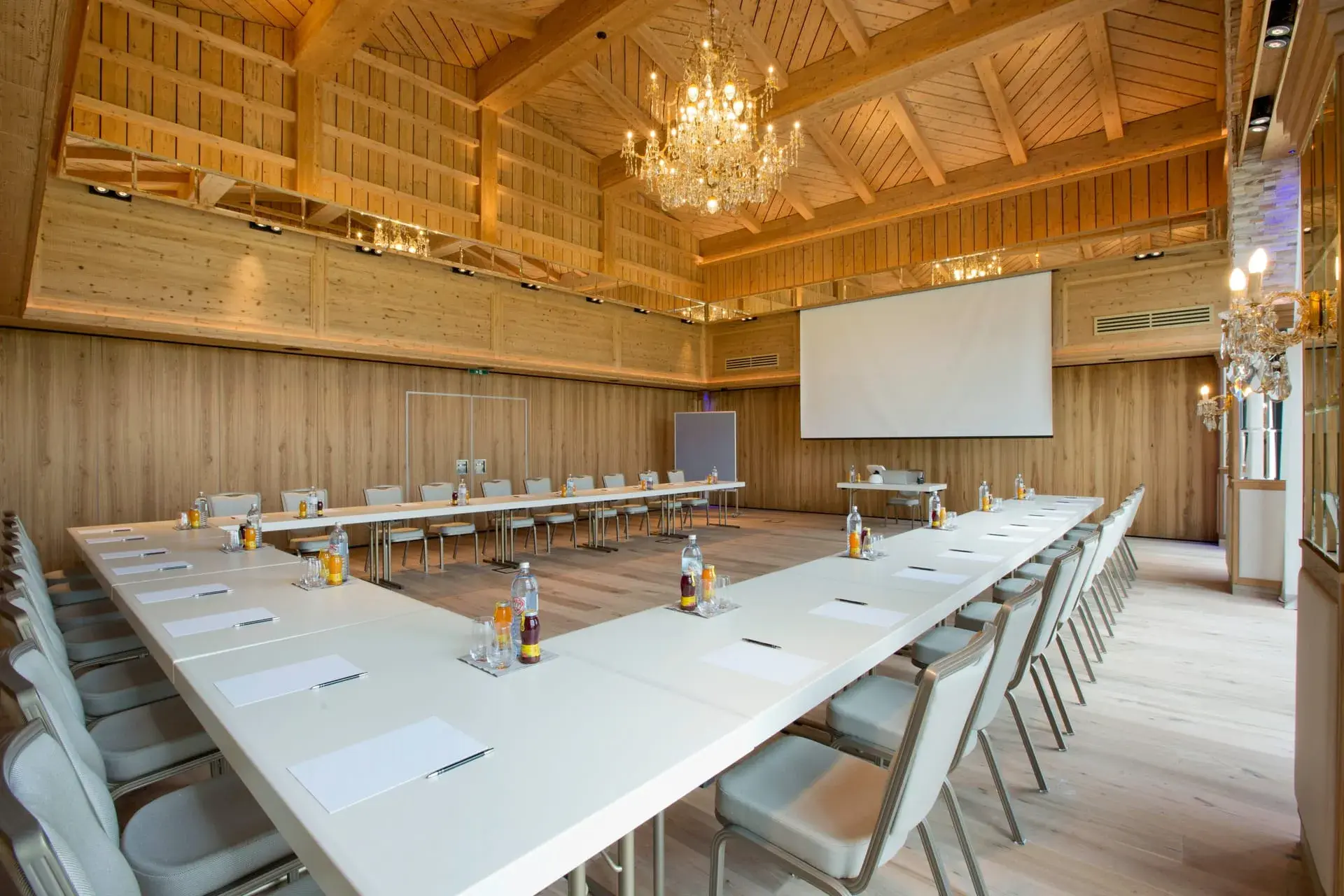 Wood-panelled seminar room with long table and screen at the Greenvieh Chalet, Mieming Plateau